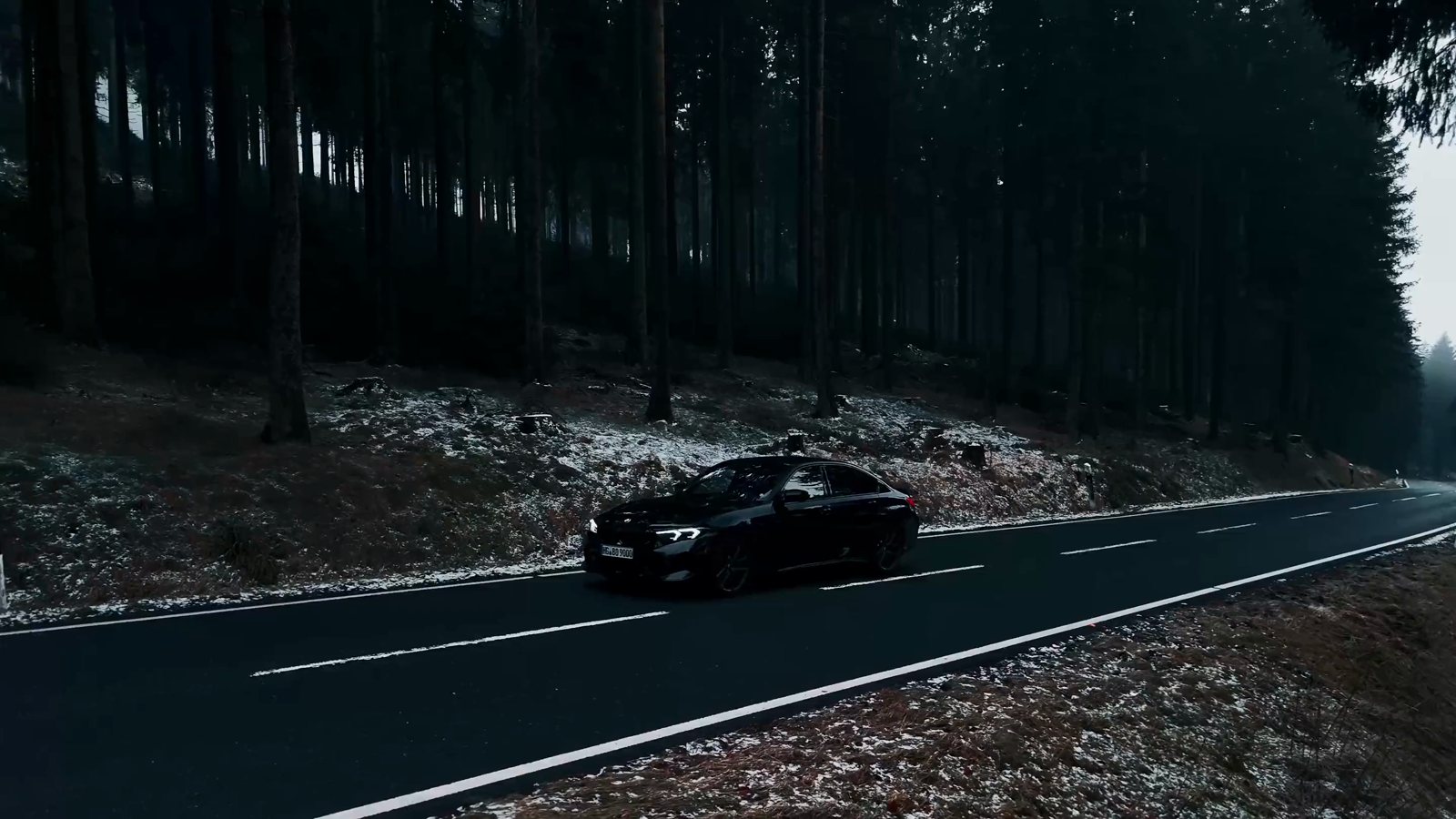 A black car on a snowy forest road, first frame of the film